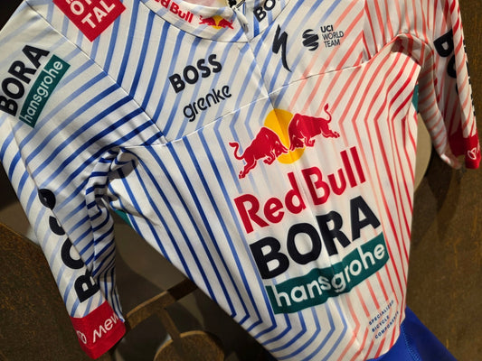 Anzug - BOH von Specialized, SPECIALIZED RED BULL - BORA HANSGROHE AERO SKIN SUIT SS / EINTEILER vor USEDBIKES - OB.DE Hintergrund