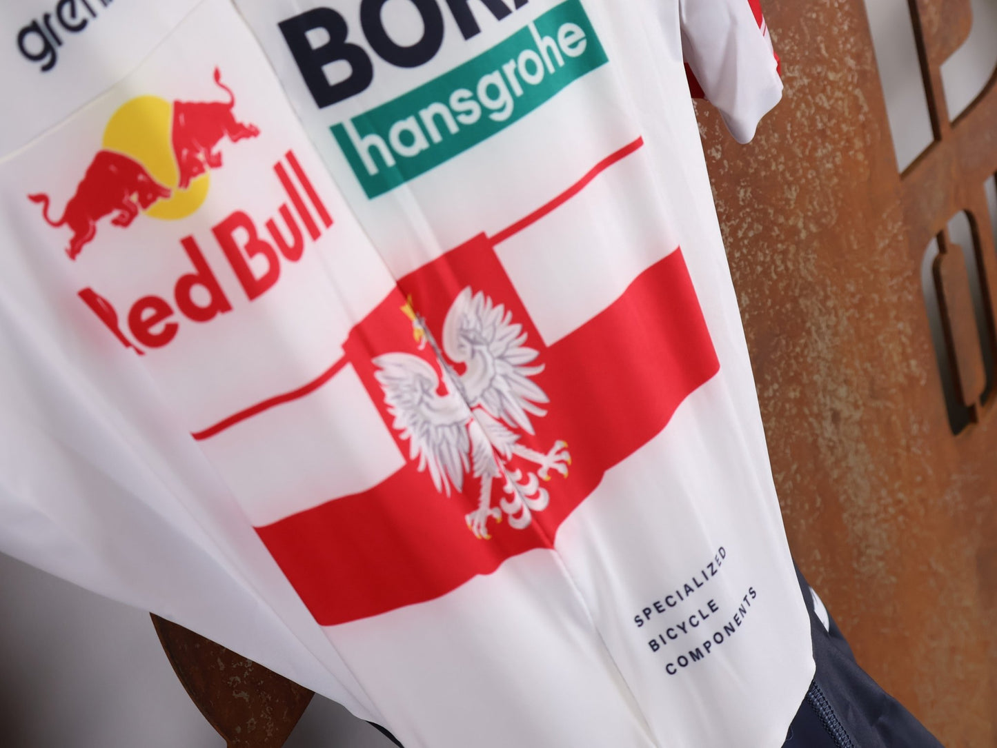 Anzug - BOH von Specialized, SPECIALIZED RED BULL - BORA HANSGROHE AERO SKIN SUIT SS / POLAND CHAMPION vor USEDBIKES - OB.DE Hintergrund