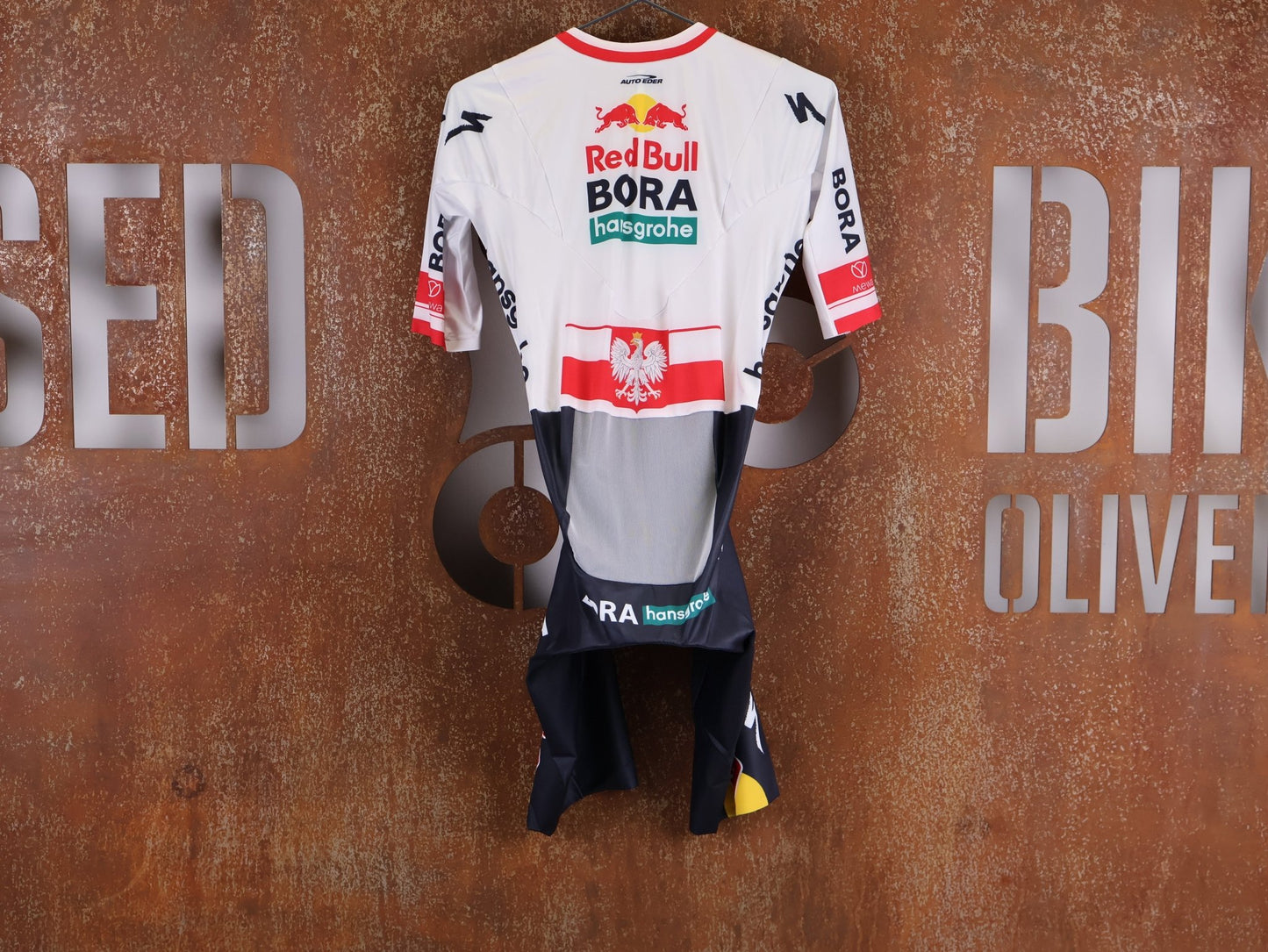 Anzug - BOH von Specialized, SPECIALIZED RED BULL - BORA HANSGROHE AERO SKIN SUIT SS / POLAND CHAMPION vor USEDBIKES - OB.DE Hintergrund