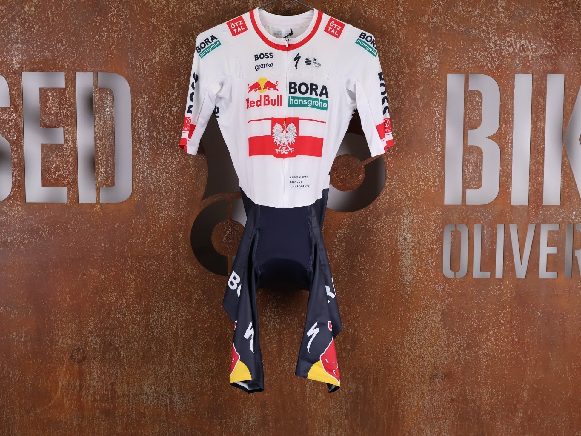 Anzug - BOH von Specialized, SPECIALIZED RED BULL - BORA HANSGROHE AERO SKIN SUIT SS / POLAND CHAMPION vor USEDBIKES - OB.DE Hintergrund