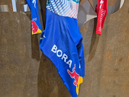 Anzug - BOH von Specialized, SPECIALIZED RED BULL - BORA HANSGROHE AERO SKIN SUIT TDF / ROGLIC vor USEDBIKES - OB.DE Hintergrund