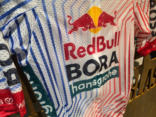 Kurzarm Trikot - BOH von Specialized, SPECIALIZED RED BULL - BORA HANSGROHE LIGHTWEIGHT JERSEY SS TDF / KURZARM TRIKOT vor USEDBIKES - OB.DE Hintergrund