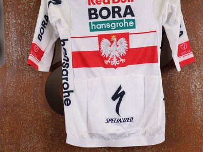 Kurzarm Trikot - BOH von Specialized, SPECIALIZED RED BULL - BORA HANSGROHE RACE JERSEY SS / POLAND CHAMPION vor USEDBIKES - OB.DE Hintergrund