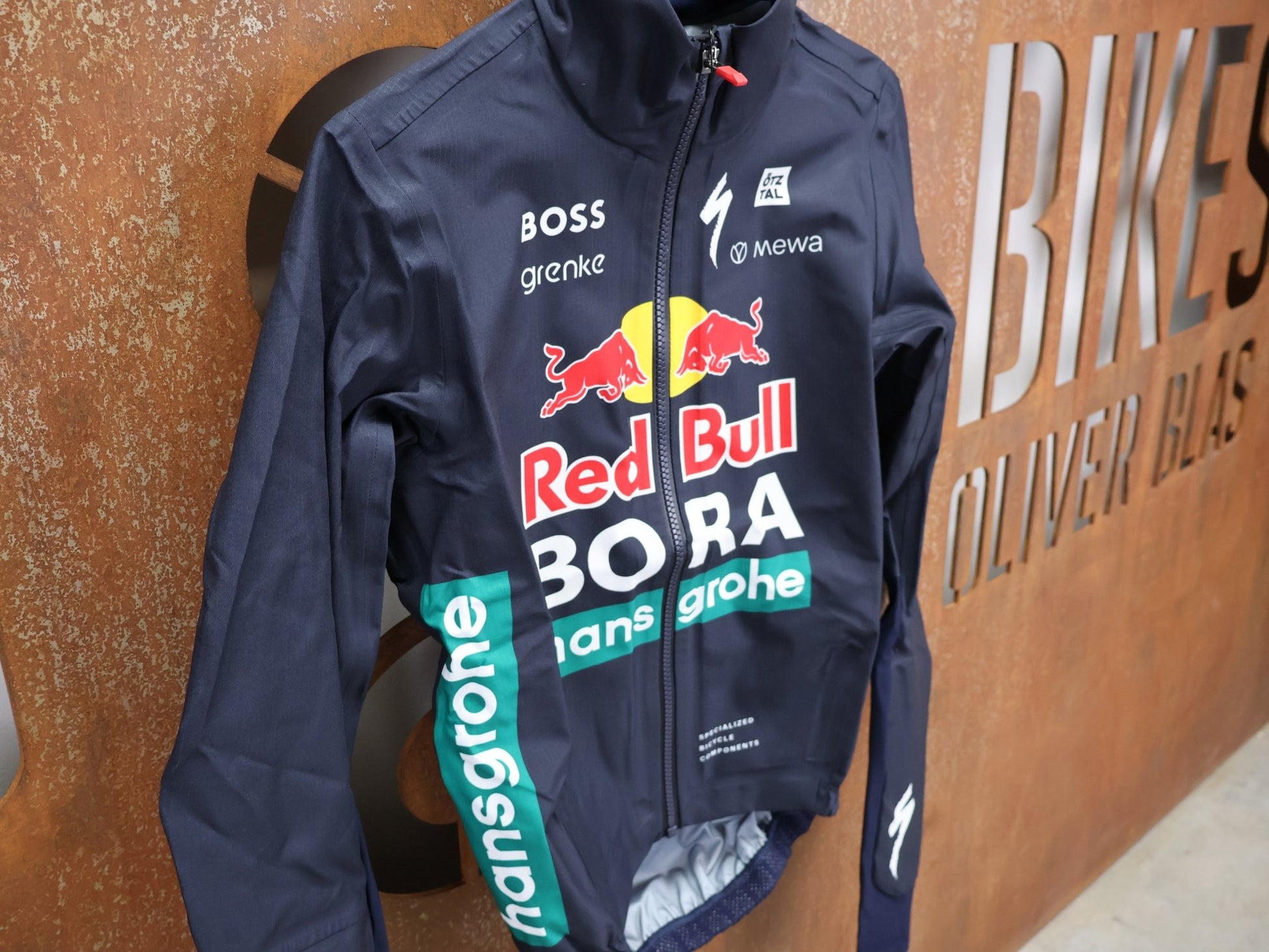 Regenbekleidung - BOH von Specialized, SPECIALIZED RED BULL - BORA HANSGROHE RAIN JACKET / WASSERDICHTE PRO TEAM REGENJACKE vor USEDBIKES - OB.DE Hintergrund