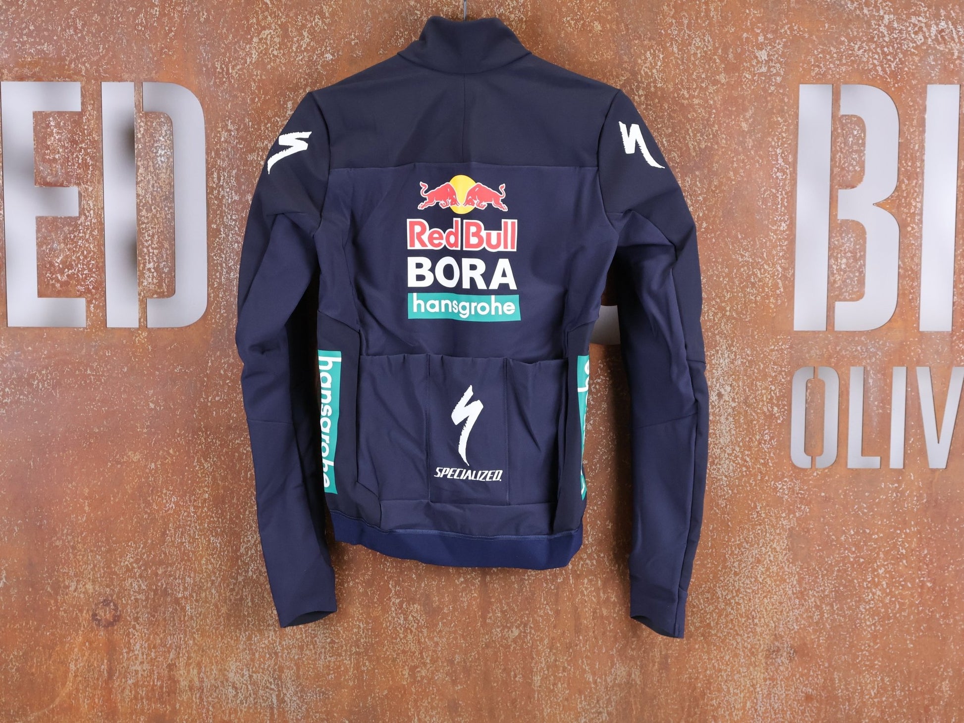 Langarm Trikot - BOH von Specialized, SPECIALIZED RED BULL - BORA HANSGROHE SOFTSHELL JACKET / WINTERJACKE vor USEDBIKES - OB.DE Hintergrund