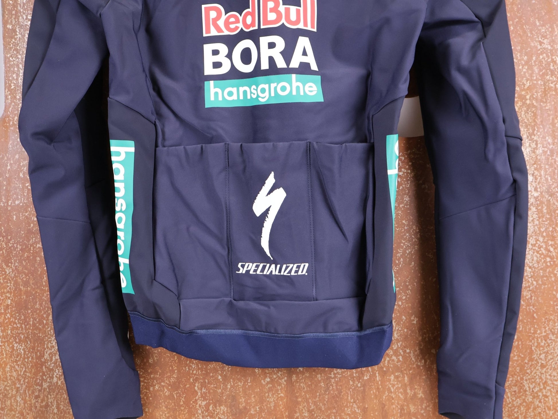 Langarm Trikot - BOH von Specialized, SPECIALIZED RED BULL - BORA HANSGROHE SOFTSHELL JACKET / WINTERJACKE vor USEDBIKES - OB.DE Hintergrund