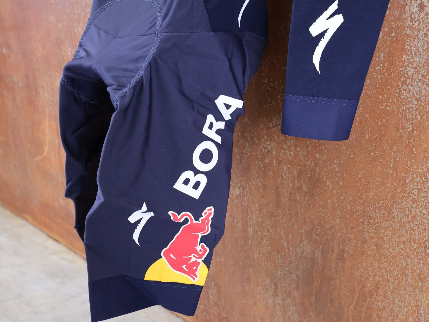 Anzug - BOH von Specialized, SPECIALIZED RED BULL - BORA HANSGROHE WET WEATHER SKIN SUIT / EINTEILER vor USEDBIKES - OB.DE Hintergrund