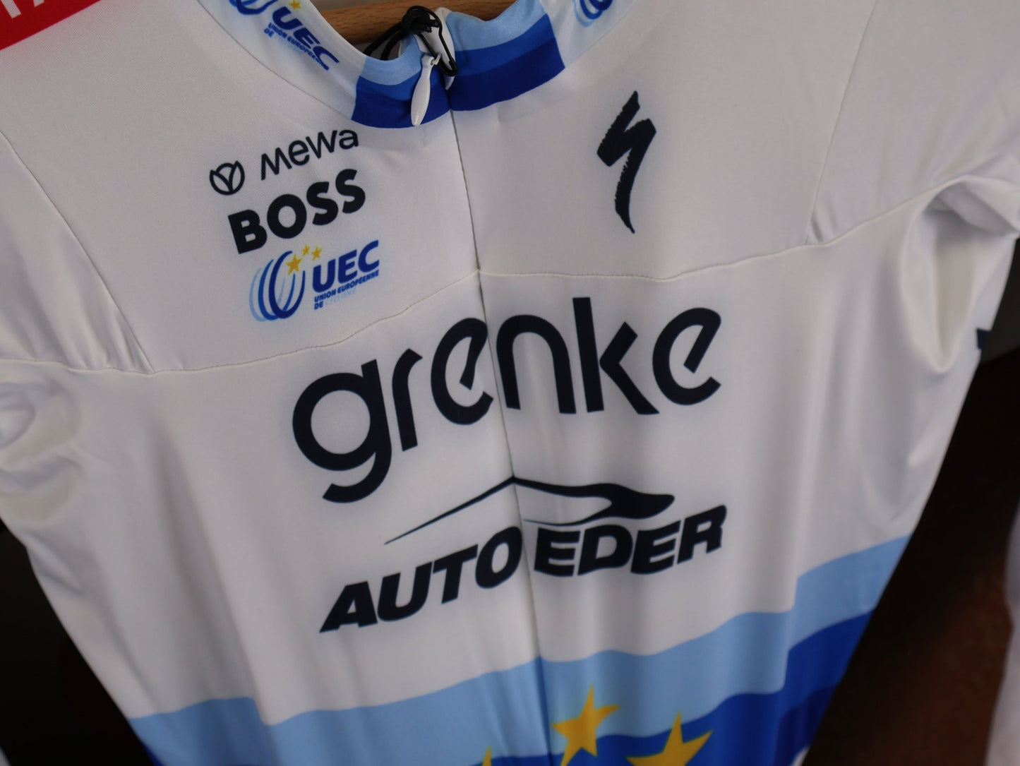 Anzug - BOH von Specialized, SPECIALIZED TGA ROOKIES OF RED BULL - BORA HANSGROHE AERO SKIN SUIT LS / EUROPEAN CHAMPION vor USEDBIKES - OB.DE Hintergrund