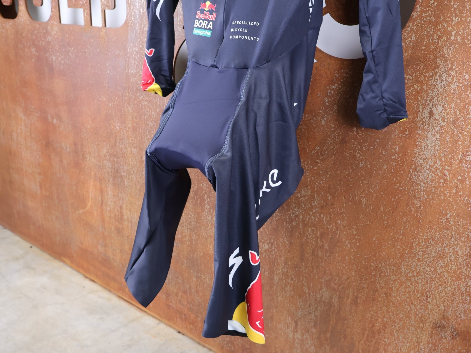 Anzug - BOH von Specialized, SPECIALIZED TGA ROOKIES OF RED BULL - BORA HANSGROHE AERO SKIN SUIT LS / LANGARM EINTEILER vor USEDBIKES - OB.DE Hintergrund