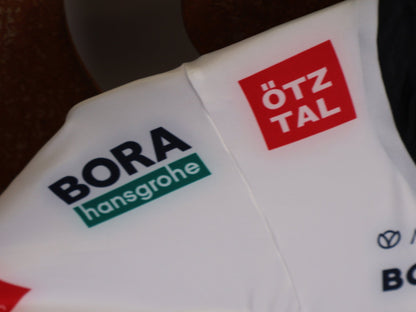 Anzug - BOH von Specialized, SPECIALIZED TGA ROOKIES OF RED BULL - BORA HANSGROHE AERO SKIN SUIT LS / SOUTH AFRICA CHAMPION vor USEDBIKES - OB.DE Hintergrund