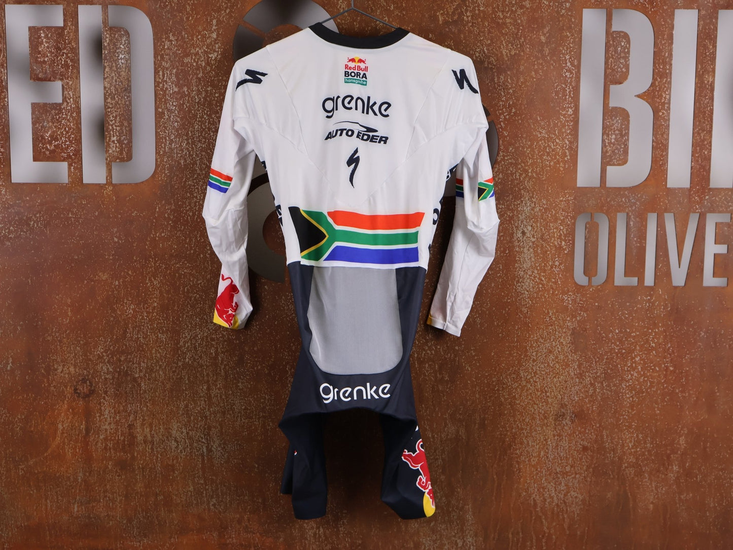 Anzug - BOH von Specialized, SPECIALIZED TGA ROOKIES OF RED BULL - BORA HANSGROHE AERO SKIN SUIT LS / SOUTH AFRICA CHAMPION vor USEDBIKES - OB.DE Hintergrund