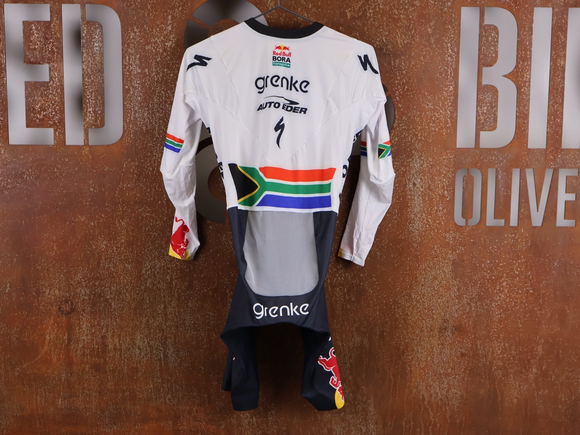 Anzug - BOH von Specialized, SPECIALIZED TGA ROOKIES OF RED BULL - BORA HANSGROHE AERO SKIN SUIT LS / SOUTH AFRICA CHAMPION vor USEDBIKES - OB.DE Hintergrund
