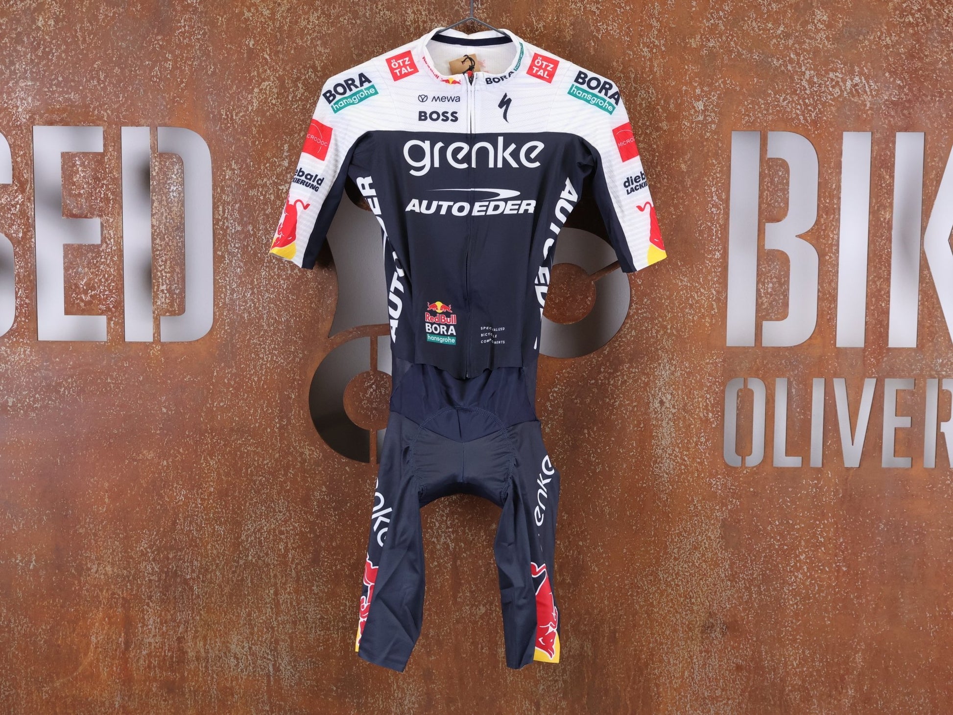 Anzug - BOH von Specialized, SPECIALIZED TGA ROOKIES OF RED BULL - BORA HANSGROHE ROAD SKIN SUIT SS / EINTEILER KURZ vor USEDBIKES - OB.DE Hintergrund