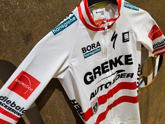 Kurzarm Trikot - U19 von Sportful, SPORTFUL GRENKE - AUTO EDER BOMBER JERSEY / KURZARM TRIKOT / ÖSTERREICHISCHER MEISTER in variant_title vor USEDBIKES - OB.DE Hintergrund