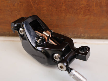Bremse von Sram, SRAM Code Silver Stealth Bremssattel 4-Kolben Black vor USEDBIKES-OB.DE Hintergrund