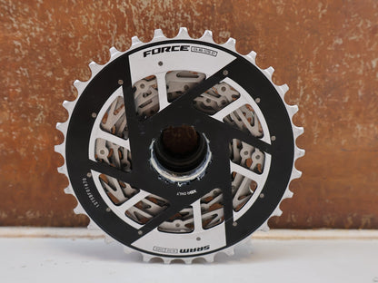 Kassette & Zahnkränze von Sram, SRAM FORCE XG 1270 E1 KASSETTE ZAHNKRANZ 10-33 ZÄHNE vor USEDBIKES-OB.DE Hintergrund