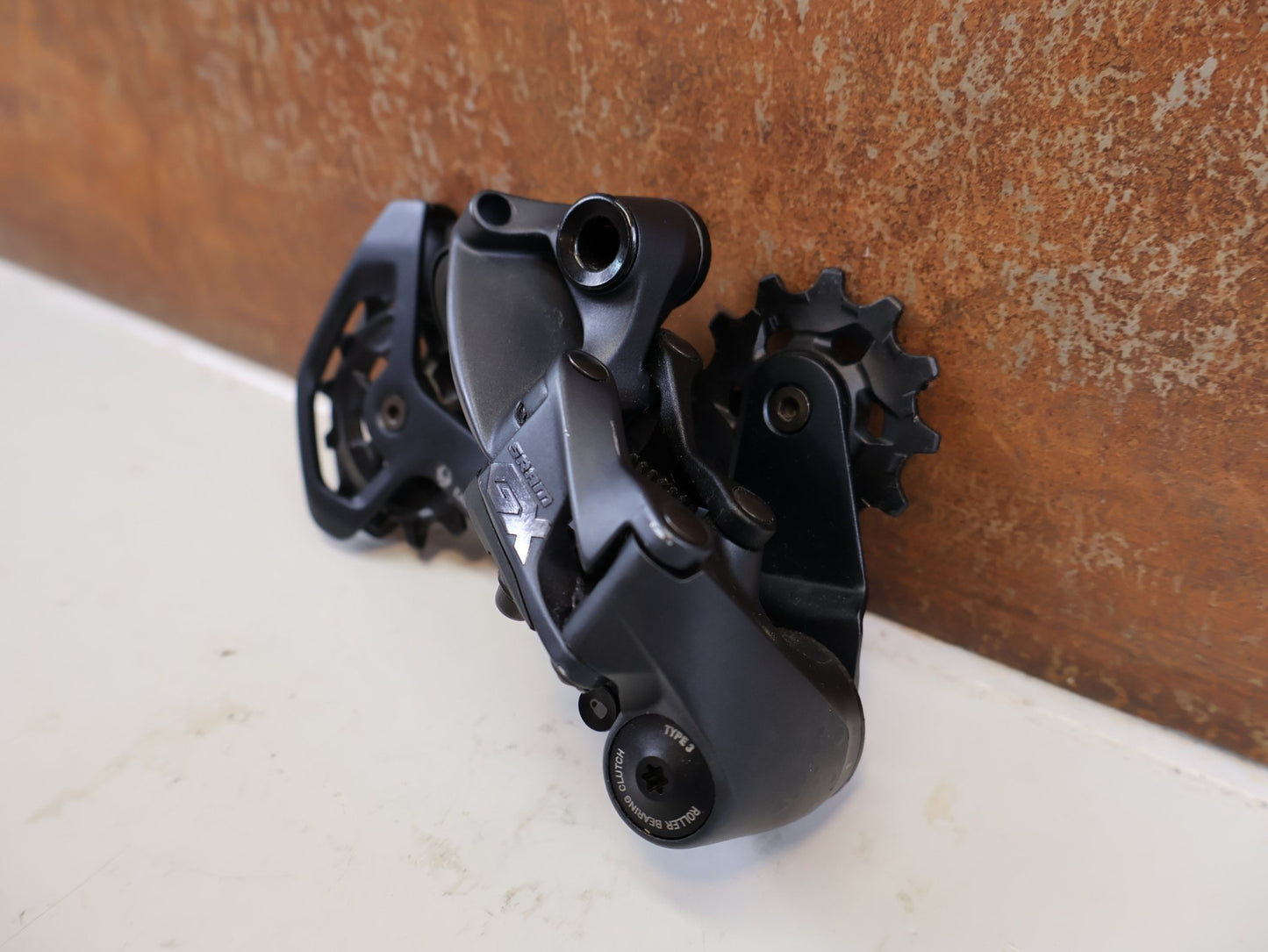Schaltungsteile von Sram, SRAM GX EAGLE SCHALTWERK 12-FACH TYPE 3.0 LUNAR GRAU 52T vor USEDBIKES-OB.DE Hintergrund
