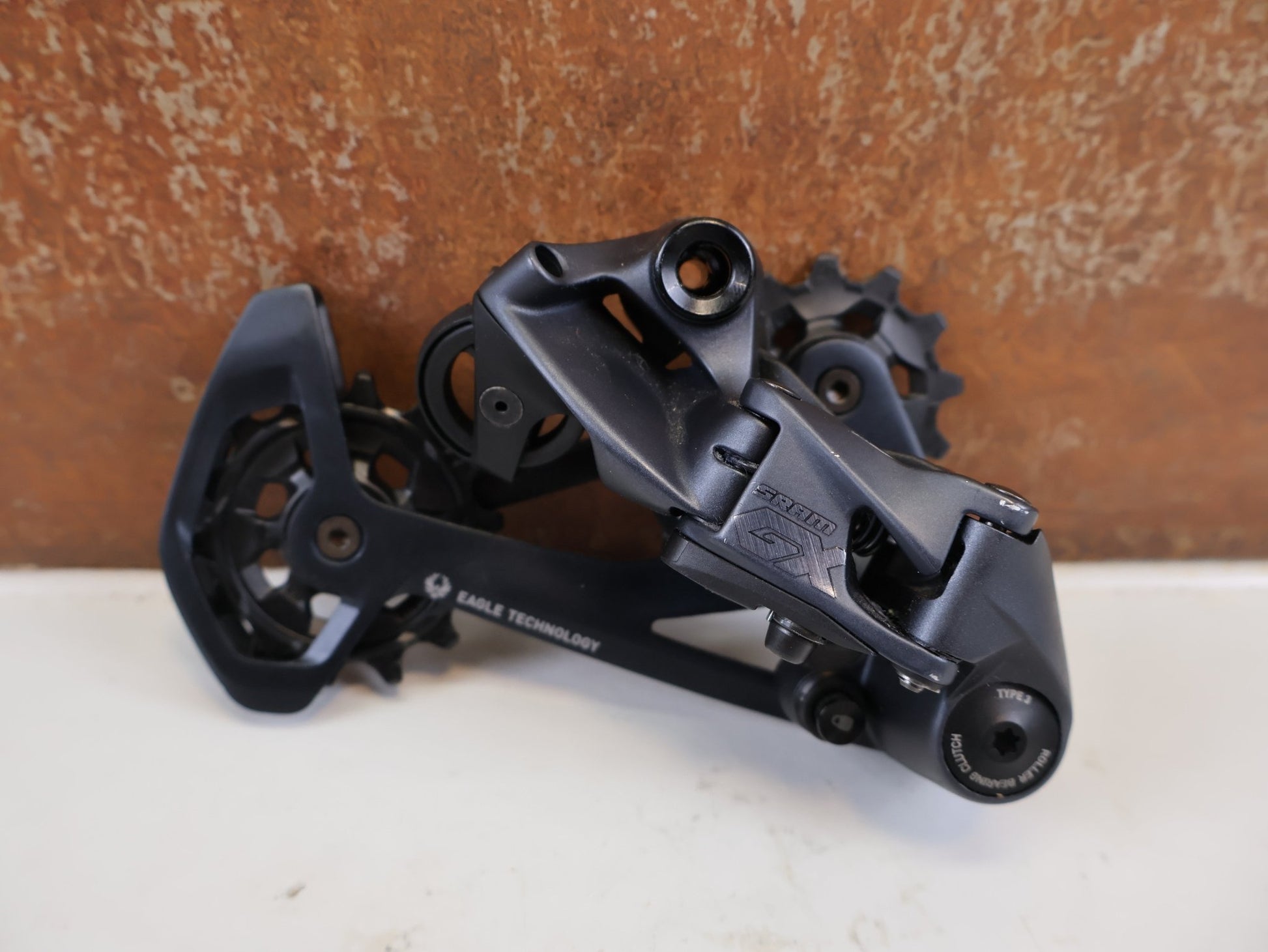 Schaltungsteile von Sram, SRAM GX EAGLE SCHALTWERK 12-FACH TYPE 3.0 LUNAR GRAU 52T vor USEDBIKES-OB.DE Hintergrund