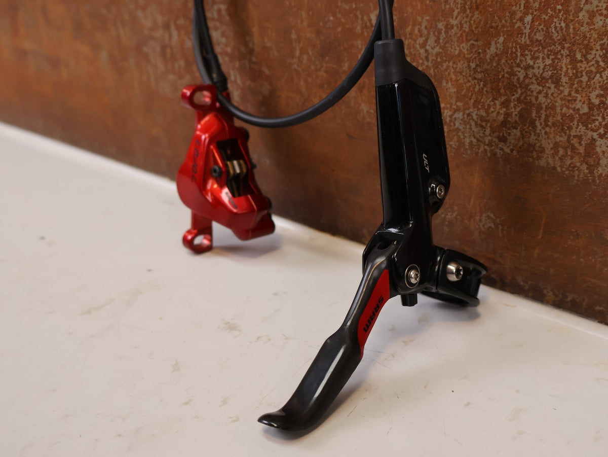 Bremse von Sram, SRAM Level Ultimate Bremsen Set Red Nino Schurter vor USEDBIKES-OB.DE Hintergrund