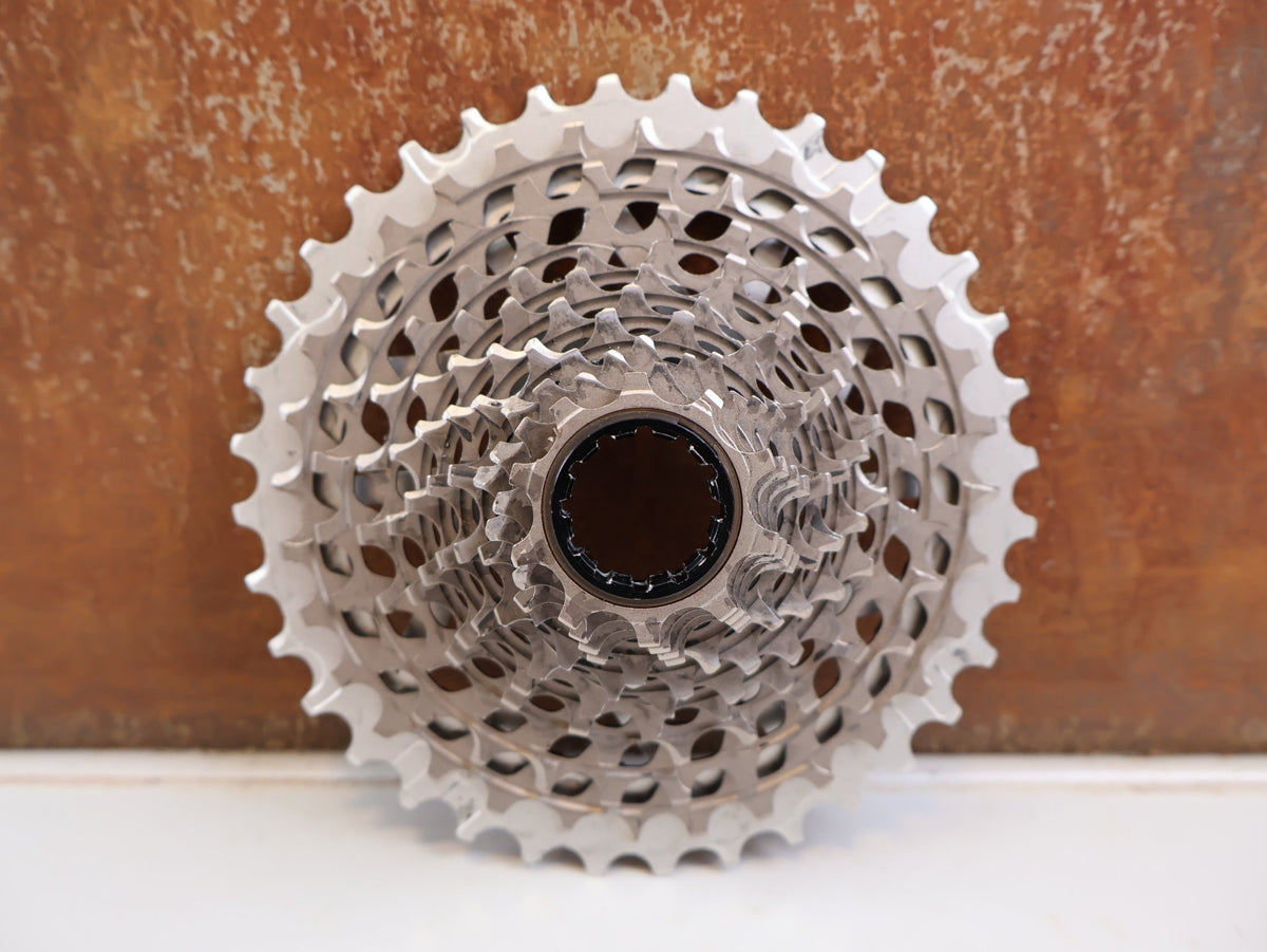 Kassette & Zahnkränze von Sram, SRAM RED XG-1290 E1 12-fach Kassette 10-36T X-Dome Silver vor USEDBIKES-OB.DE Hintergrund