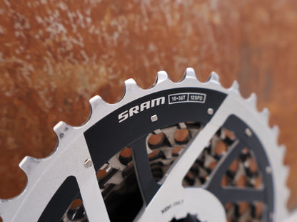 Kassette & Zahnkränze von Sram, SRAM RED XG-1290 E1 12-fach Kassette 10-36T X-Dome Silver vor USEDBIKES-OB.DE Hintergrund