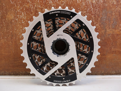 Kassette & Zahnkränze von Sram, SRAM RED XG-1290 E1 12-fach Kassette 10-36T X-Dome Silver vor USEDBIKES-OB.DE Hintergrund