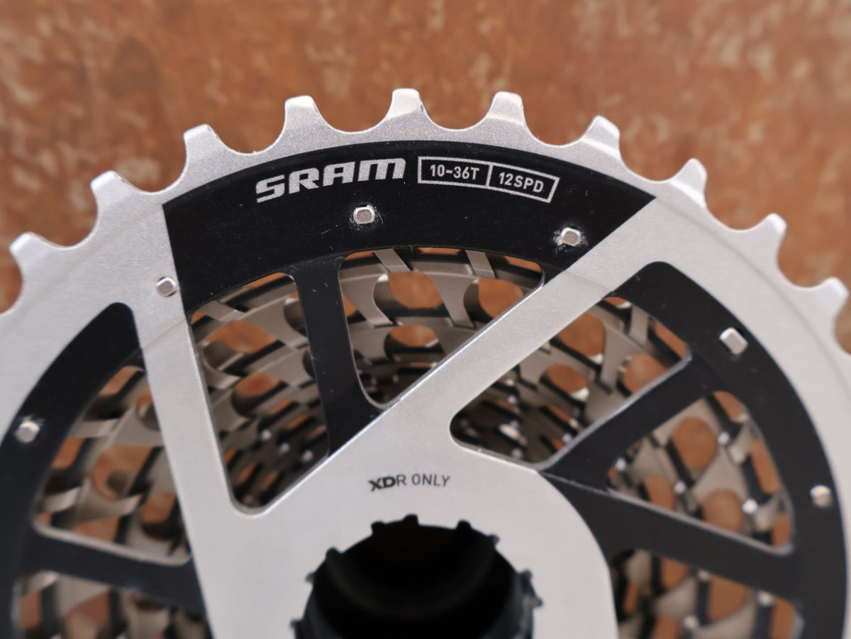 Kurbel von Sram, SRAM RED XG-1290 E1 12-fach Kassette 10-36T X-Dome Silver vor USEDBIKES-OB.DE Hintergrund