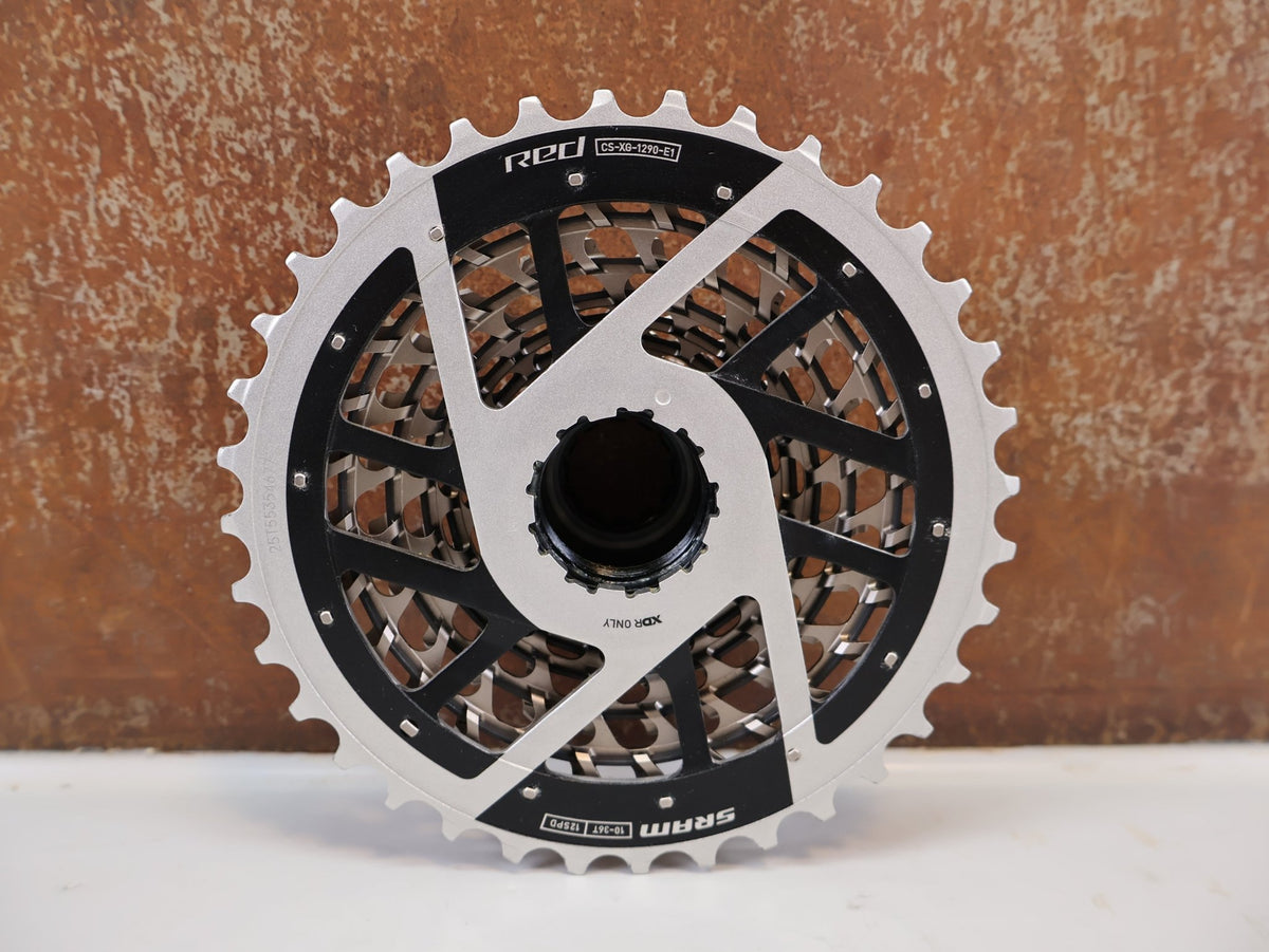Kurbel von Sram, SRAM RED XG-1290 E1 12-fach Kassette 10-36T X-Dome Silver vor USEDBIKES-OB.DE Hintergrund
