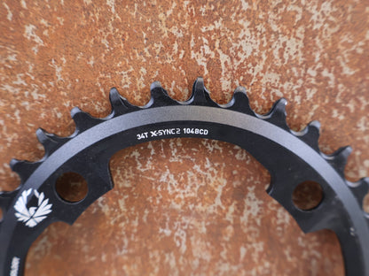 Kettenblatt von Sram, SRAM X-SYNC 2 EAGLE KETTENBLATT 34T 104 MM BCD vor USEDBIKES-OB.DE Hintergrund