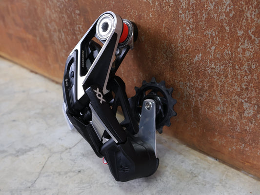 Schaltungsteile von Sram, SRAM XX EAGLE TRANSMISSION AXS T - TYPE SCHALTWERK / 12 - FACH – 10–52T – SILBER vor USEDBIKES - OB.DE Hintergrund