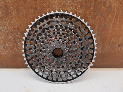 Kassette & Zahnkränze von Sram, SRAM XX Eagle XS-1297 T-Type Kassette 12-fach 10-52T Silber vor USEDBIKES-OB.DE Hintergrund