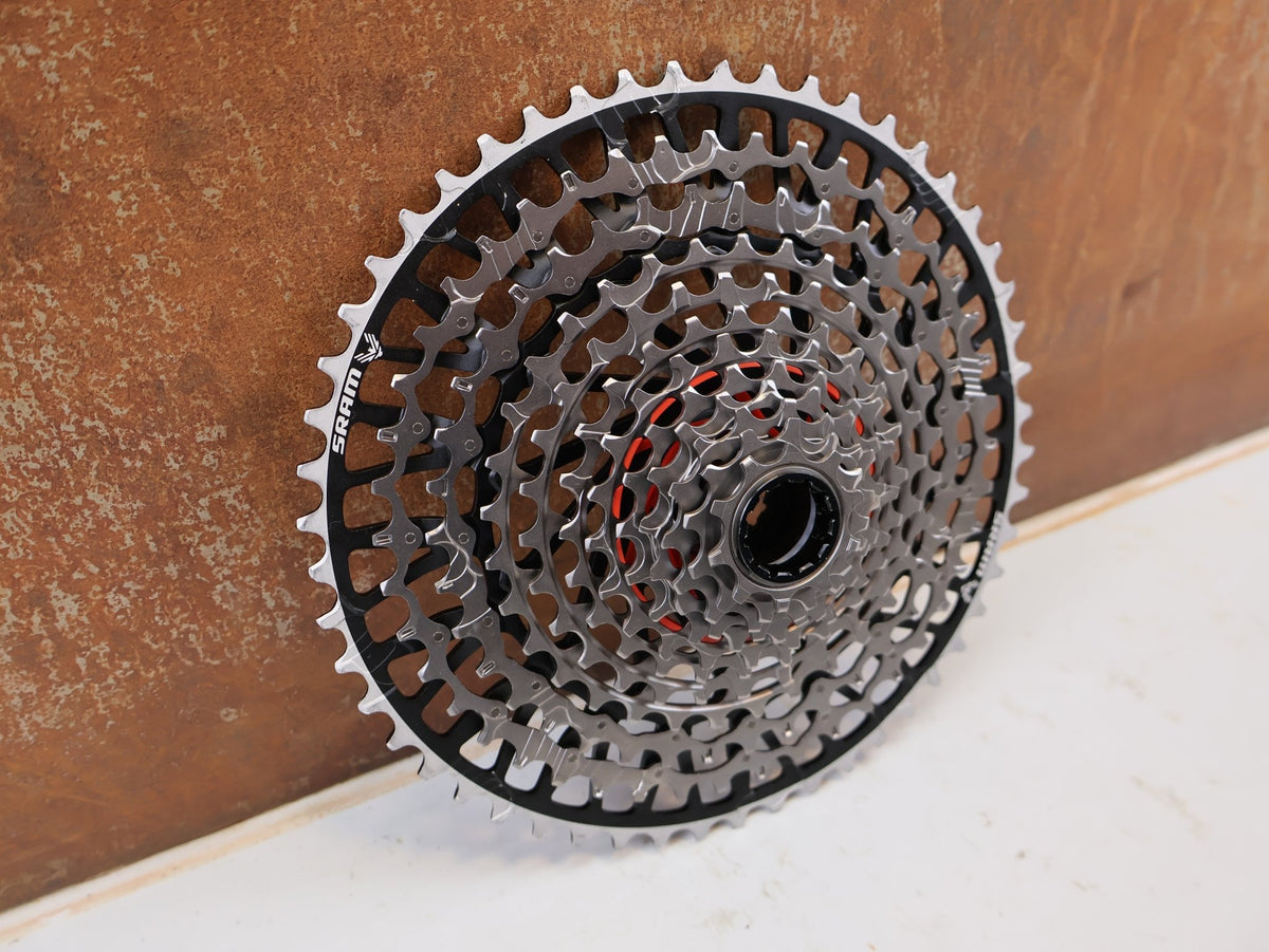 Kassette & Zahnkränze von Sram, SRAM XX Eagle XS-1297 T-Type Kassette 12-fach 10-52T Silber vor USEDBIKES-OB.DE Hintergrund