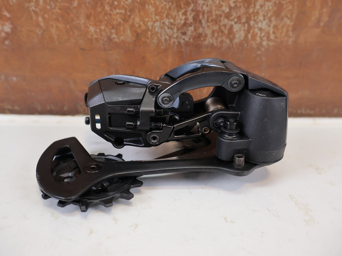 Schaltungsteile von Sram, SRAM XX1 Eagle AXS 12-fach Schaltwerk 52Z Carbon Titan vor USEDBIKES-OB.DE Hintergrund