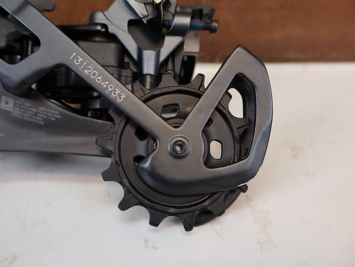 Schaltungsteile von Sram, SRAM XX1 Eagle AXS 12-fach Schaltwerk 52Z Carbon Titan vor USEDBIKES-OB.DE Hintergrund