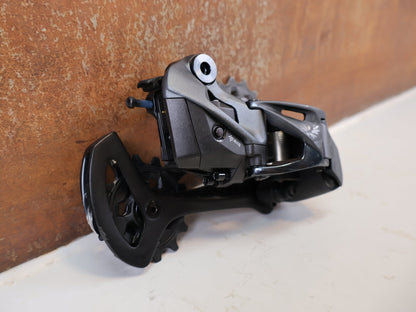 Schaltungsteile von Sram, SRAM XX1 Eagle AXS 12-fach Schaltwerk 52Z Carbon Titan vor USEDBIKES-OB.DE Hintergrund