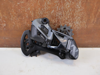 Schaltungsteile von Sram, SRAM XX1 Eagle AXS 12-fach Schaltwerk 52Z Carbon Titan vor USEDBIKES-OB.DE Hintergrund