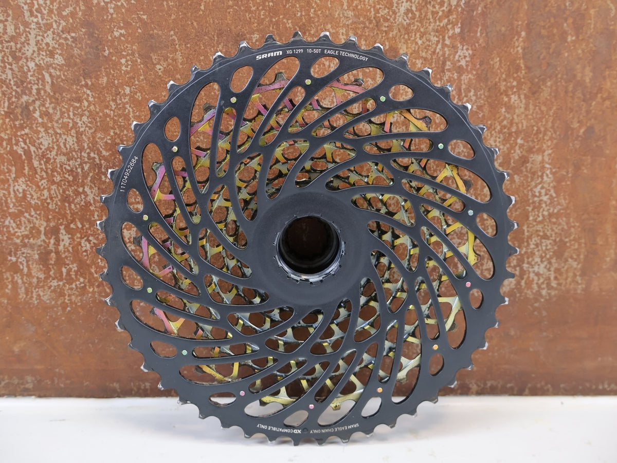 Kassette & Zahnkränze von Sram, SRAM XX1 Eagle XG-1299 Kassette 10-50T Rainbow XD 358g vor USEDBIKES-OB.DE Hintergrund