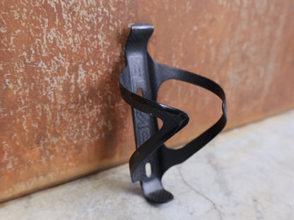 Trinkflaschen und Halter von Supacaz, SUPACAZ BLACK CARBON FLY FLASCHENHALTER / CARBON / 21 G vor USEDBIKES - OB.DE Hintergrund