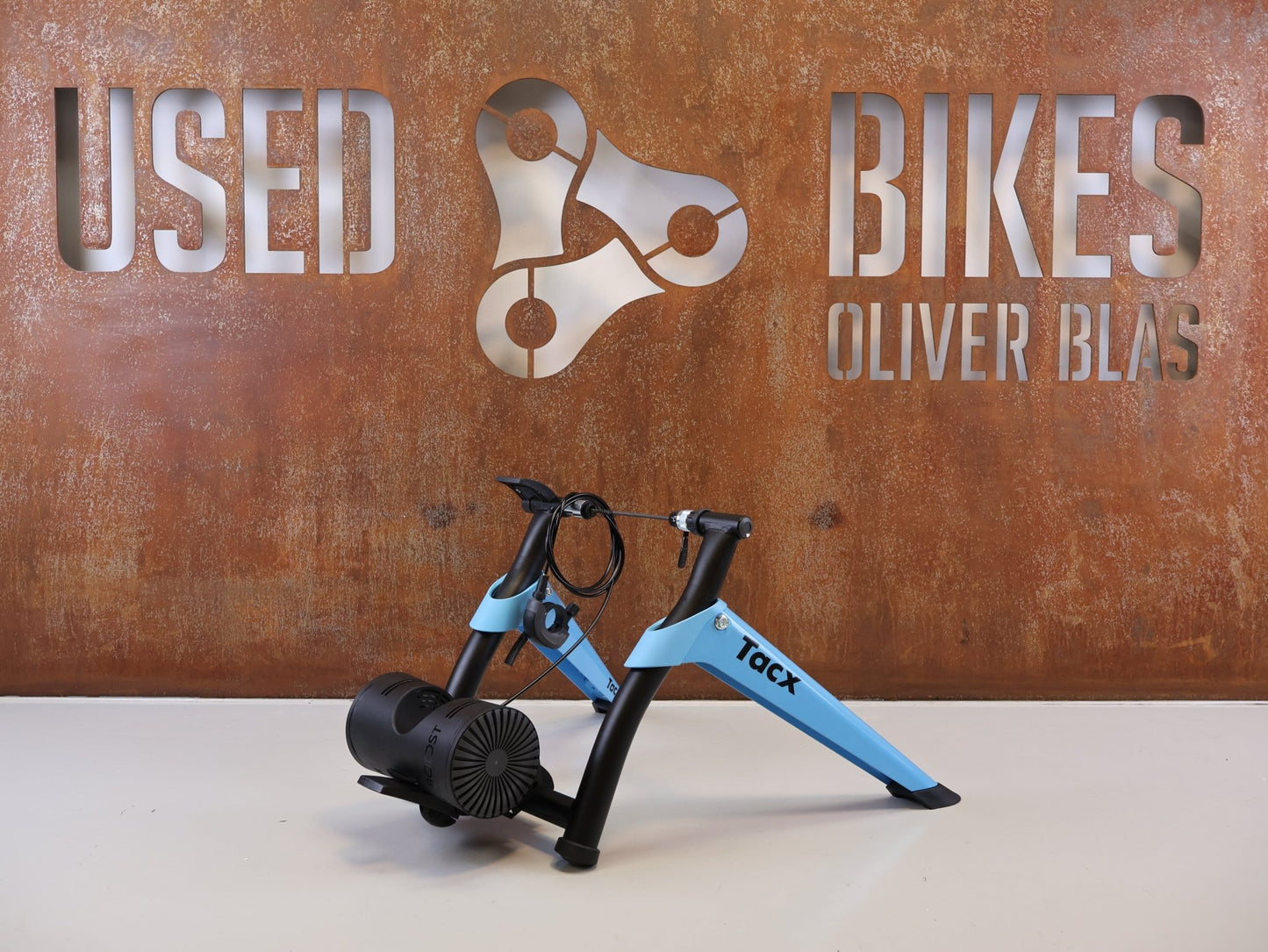 Rollentrainer von Tacx, TACX BOOST ROLLENTRAINER HEIMTRAINER INKL. VORDERRADSTÜTZE vor USEDBIKES-OB.DE Hintergrund