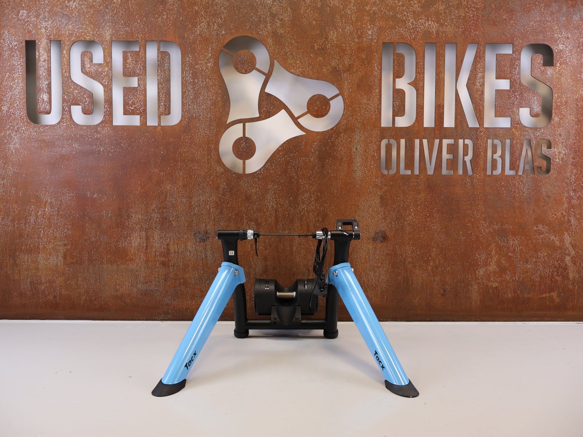Rollentrainer von Tacx, TACX BOOST ROLLENTRAINER HEIMTRAINER INKL. VORDERRADSTÜTZE vor USEDBIKES-OB.DE Hintergrund