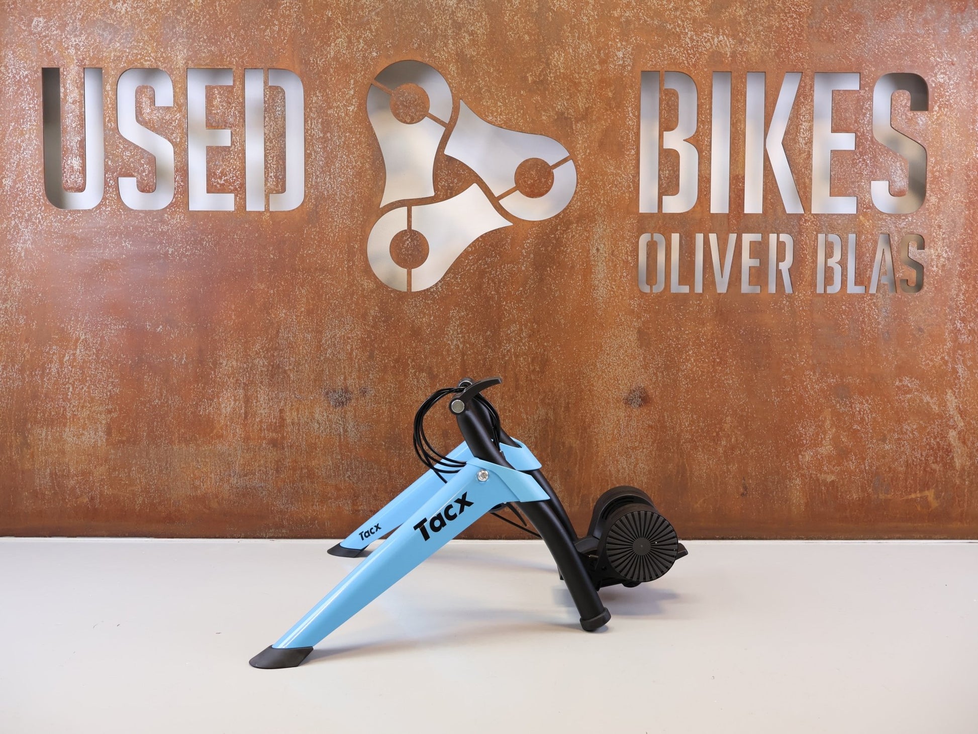 Rollentrainer von Tacx, TACX BOOST ROLLENTRAINER HEIMTRAINER INKL. VORDERRADSTÜTZE vor USEDBIKES-OB.DE Hintergrund