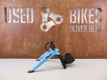 Rollentrainer von Tacx, TACX BOOST ROLLENTRAINER HEIMTRAINER INKL. VORDERRADSTÜTZE vor USEDBIKES-OB.DE Hintergrund