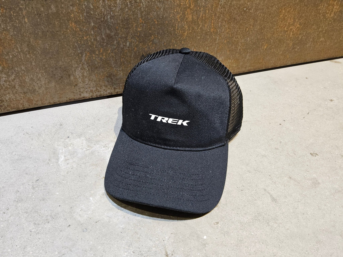 Freizeitbekleidung von Trek, TREK BLACK LOGO HAT / SNAPBACK TRUCKERCAP vor USEDBIKES - OB.DE Hintergrund