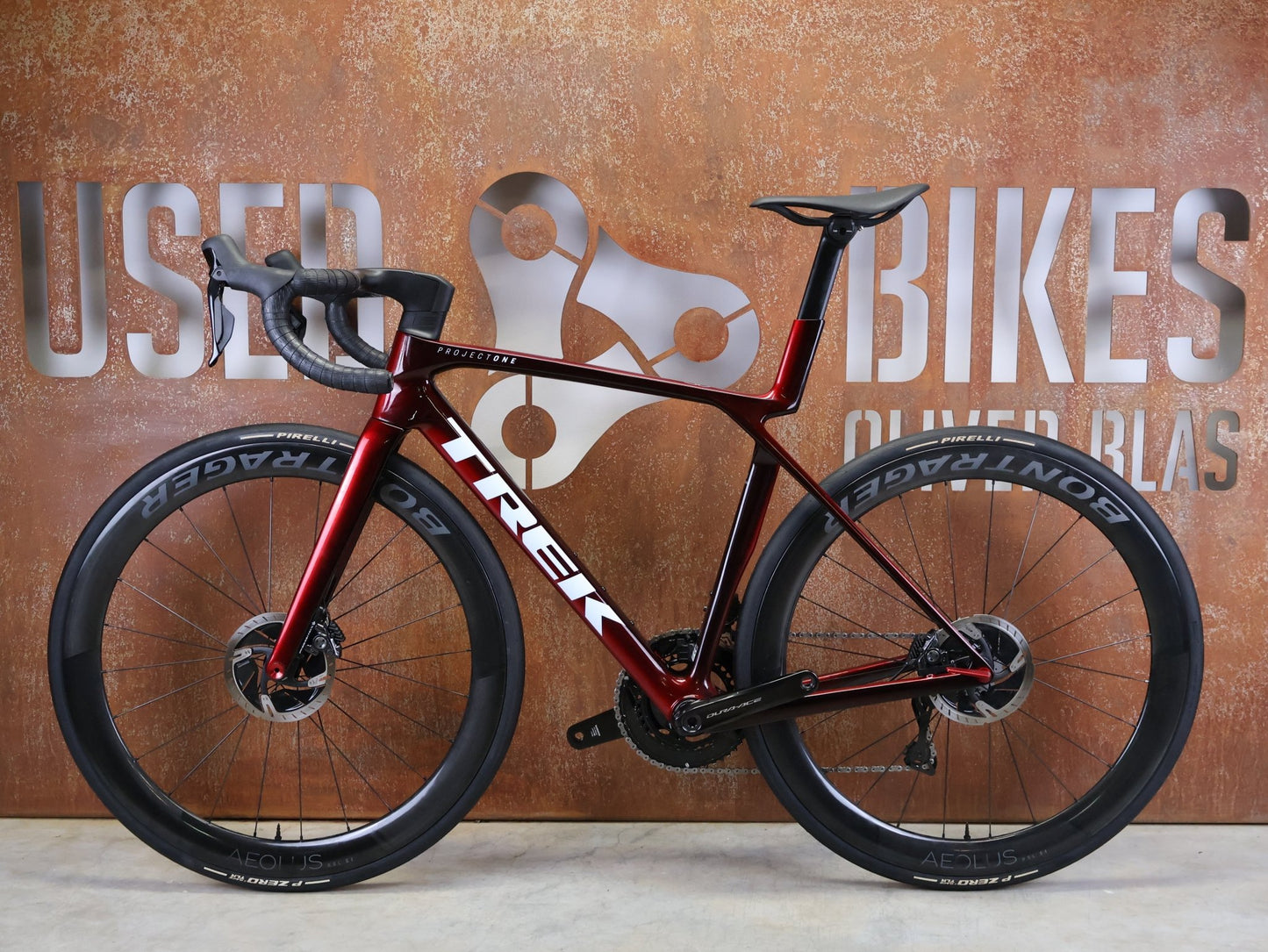 Rennrad von Trek, TREK – MADONE SLR 9 GEN 8 / DURA - ACE DI2 / CARBON RED SMOKE / M vor USEDBIKES - OB.DE Hintergrund