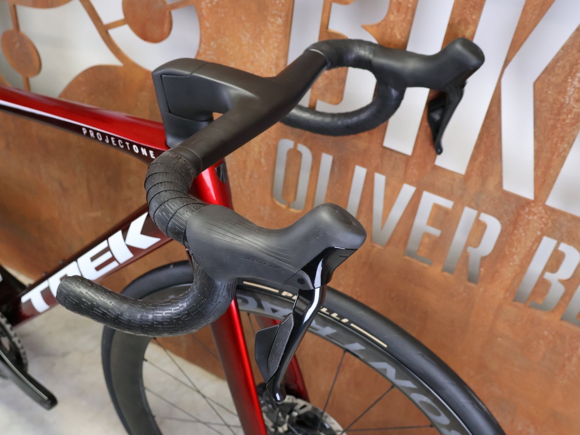 Rennrad von Trek, TREK – MADONE SLR 9 GEN 8 / DURA - ACE DI2 / CARBON RED SMOKE / M vor USEDBIKES - OB.DE Hintergrund