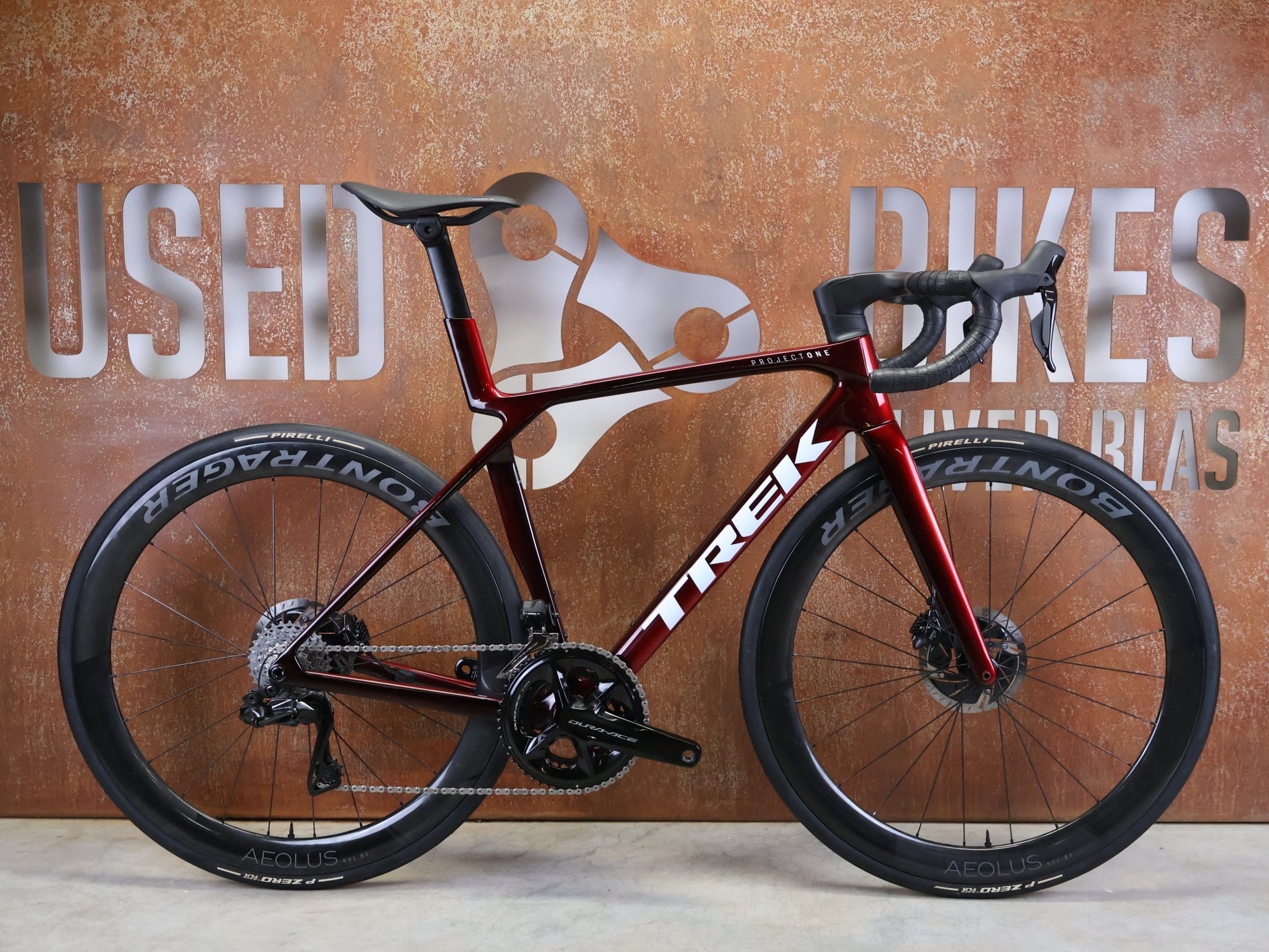 Rennrad von Trek, TREK – MADONE SLR 9 GEN 8 / DURA - ACE DI2 / CARBON RED SMOKE / M vor USEDBIKES - OB.DE Hintergrund