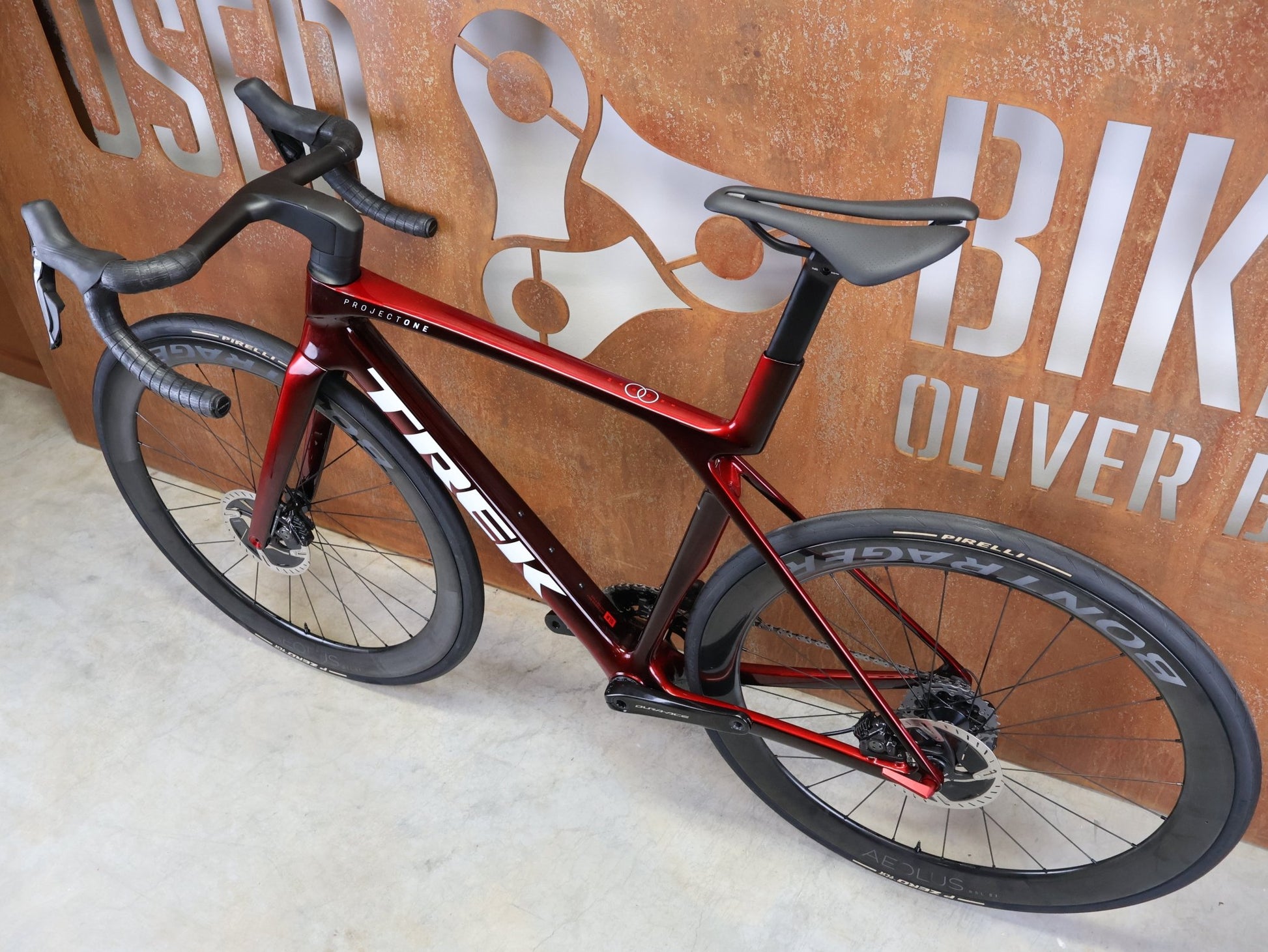 Rennrad von Trek, TREK – MADONE SLR 9 GEN 8 / DURA - ACE DI2 / CARBON RED SMOKE / M vor USEDBIKES - OB.DE Hintergrund