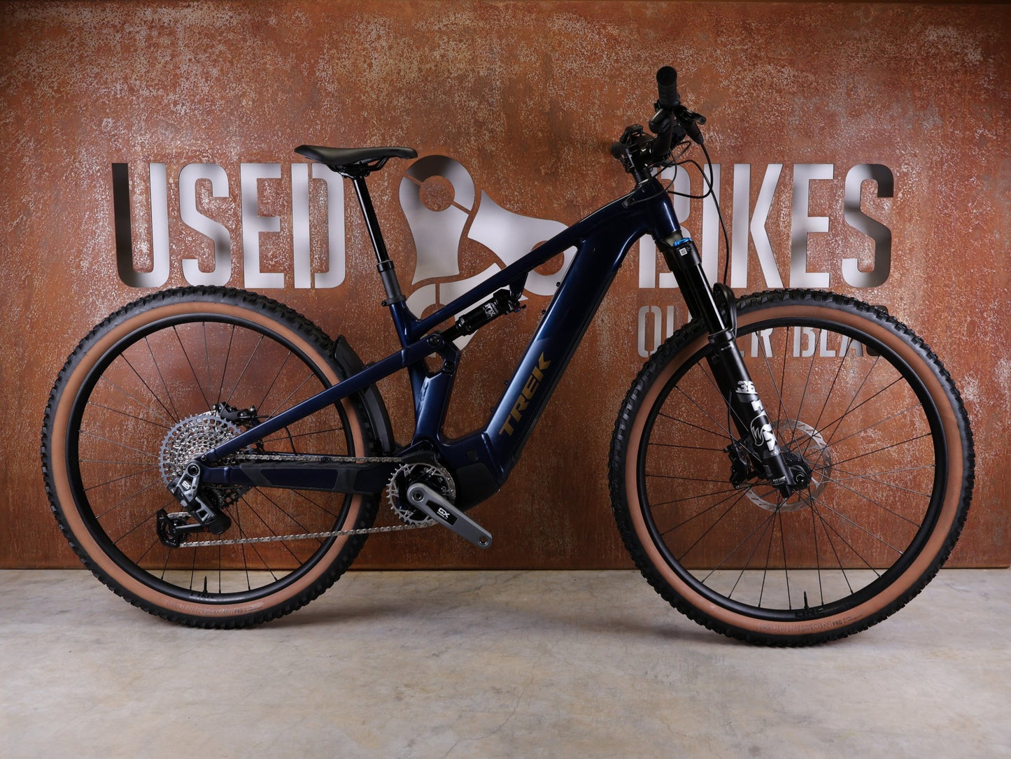 E - Mountainbike von Trek, TREK POWERFLY+ FS 8 GEN 4 / MATTE/GLOSS MULSANNE BLUE / M vor USEDBIKES - OB.DE Hintergrund