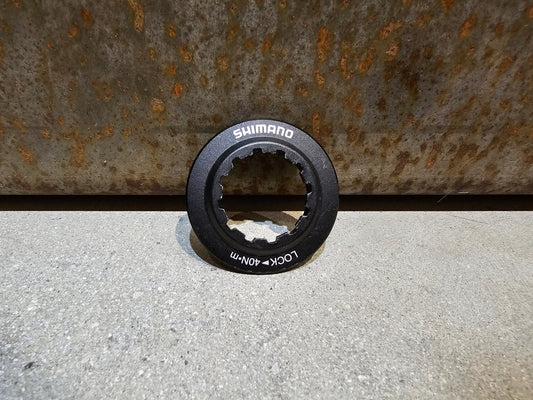 Bremsscheibe von Shimano, VERSCHLUSSRING SHIMANO CENTERLOCK BREMSSCHEIBE / SCHWARZ in variant_title vor USEDBIKES - OB.DE Hintergrund