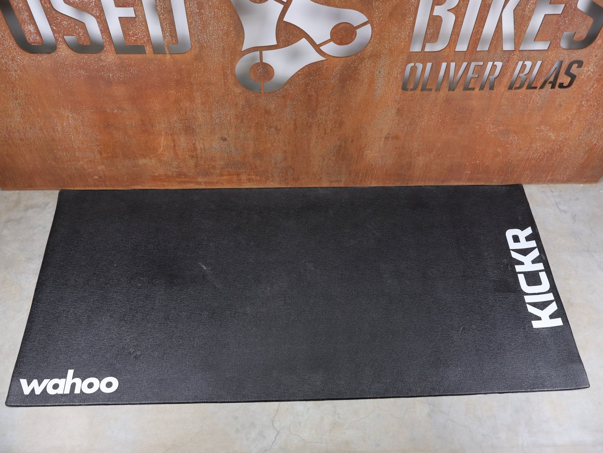 Rollentrainer & Zubehör von Wahoo, WAHOO TRAININGSMATTE FÜR HEIMTRAINER WFKICKRMAT vor USEDBIKES - OB.DE Hintergrund